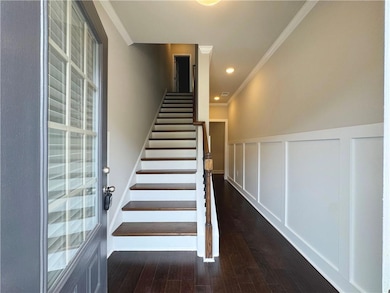 Stairway featuring ornamental molding, wood finished floors, a decorative wall, wainscoting, and recessed lighting