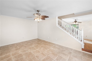 Empty room featuring a ceiling fan, stairway, and crown molding