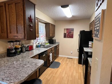 Kitchen with black appliances, sink, light wood-ty