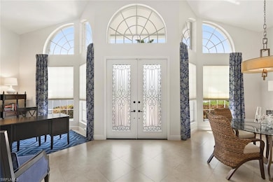 Entryway with a towering ceiling, baseboards, french doors, and tile patterned flooring