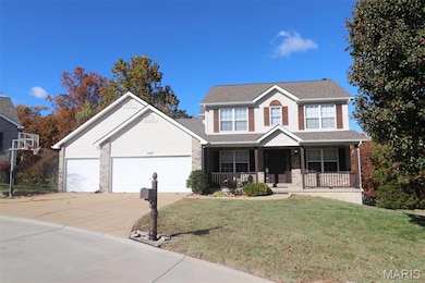 Traditional-style house with a porch, driveway, a front yard, and brick siding