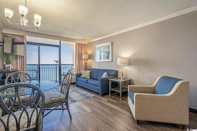 Living room featuring dark wood-style flooring, a water view, and crown molding