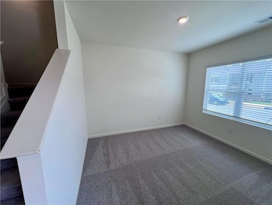 Carpeted spare room featuring baseboards and stairway