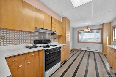 Kitchen featuring range with gas cooktop, a paneled ceiling, light countertops, under cabinet range hood, and wallpapered walls