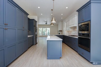 Kitchen with stainless steel appliances, a kitchen island, light countertops, decorative backsplash, and a peninsula