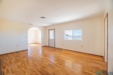 Spare room featuring arched walkways and light wood-style floors