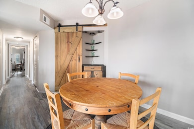 Dining area featuring newly installed LVP flooring, baseboards, a barn door, and a chandelier