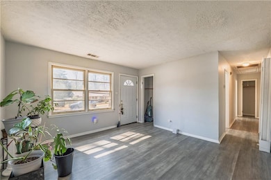 Entryway featuring a textured ceiling, visible vents, dark wood-style flooring, and baseboards