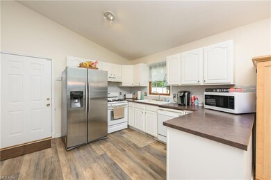 Kitchen featuring backsplash, white cabinets, vaul
