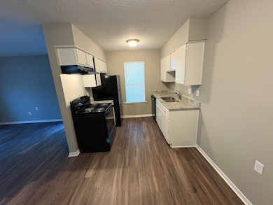 Kitchen featuring black electric range, white cabinets, a textured ceiling, and dark wood finished floors