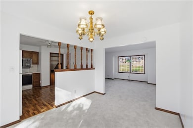 dining room featuring a chandelier, light colored carpet, access to kitchen