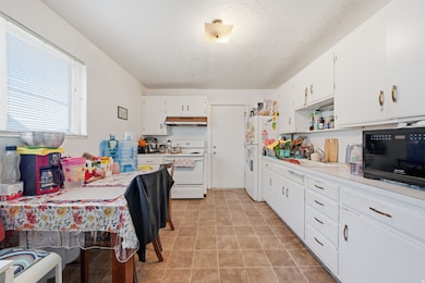 Kitchen with light countertops, white appliances, white cabinetry, open shelves, and a textured ceiling