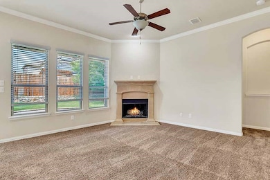 Living room featuring crown molding, carpet flooring, a high end fireplace, and a ceiling fan