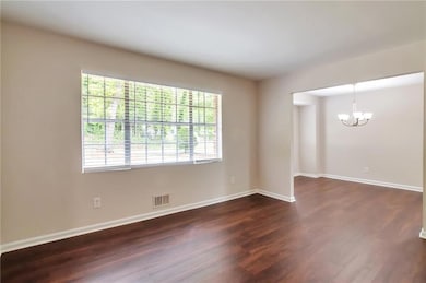 Empty room with a chandelier, dark wood-style floo