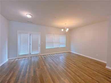 Unfurnished room with a chandelier, dark wood-type flooring, and baseboards