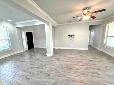 Unfurnished living room with crown molding, light wood-style floors, and a ceiling fan