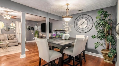 Dining space featuring ceiling fan, wood finished floors, and a textured ceiling
