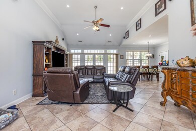 Living area featuring crown molding, vaulted ceiling, recessed lighting, a ceiling fan, and light tile patterned floors