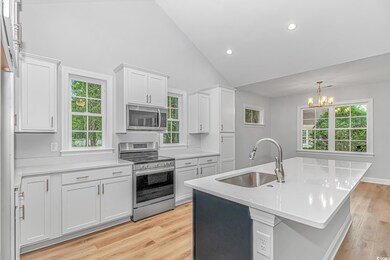 Kitchen with stainless steel appliances, a sink, a chandelier, light countertops, and white cabinetry