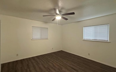 Spare room with dark wood-style floors, baseboard