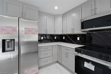 Kitchen with appliances with stainless steel finishes, tasteful backsplash, light marble finish floors, light stone countertops, and recessed lighting