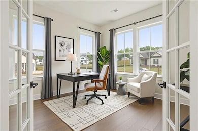 Home office featuring dark wood finished floors, french doors, and baseboards