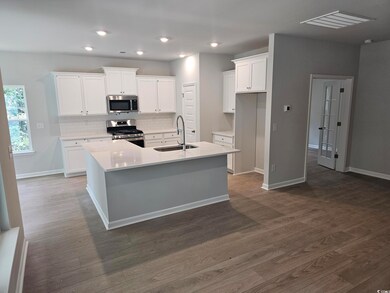 Kitchen featuring stainless steel appliances, a sink, a center island with sink, decorative backsplash, and white cabinetry