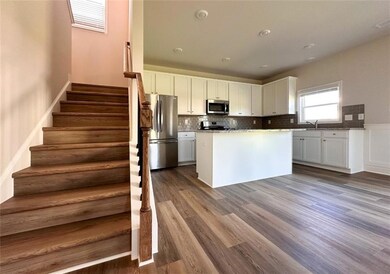 Kitchen with stainless steel appliances, white cabinetry, dark wood-style floors, a kitchen island, and a sink