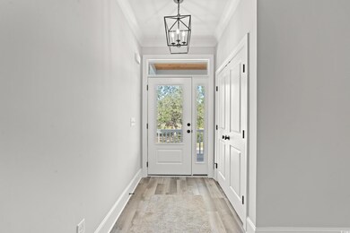 Doorway with a chandelier, crown molding, and ligh