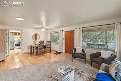 Living area with light wood-style floors, ceiling fan, and baseboards