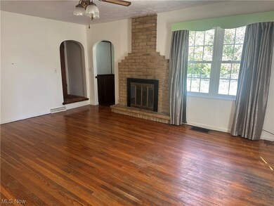 Unfurnished living room with brick wall, a fireplace, dark hardwood floors, and ceiling fan