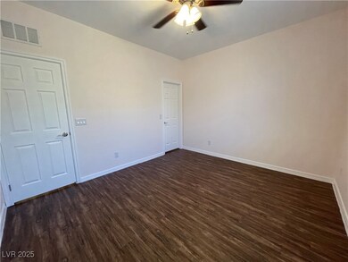 Empty room featuring a ceiling fan, dark wood fini