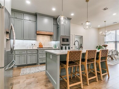 Kitchen with a breakfast bar, pendant lighting, light hardwood / wood-style flooring, and stainless steel appliances