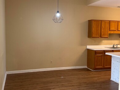 Kitchen featuring dark wood finished floors, a sink, brown cabinetry, light countertops, and baseboards