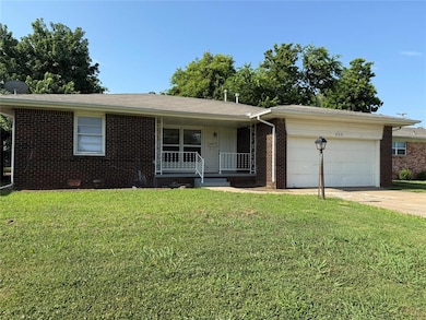 Single story home with a porch, an attached garage, concrete driveway, brick siding, and a front yard