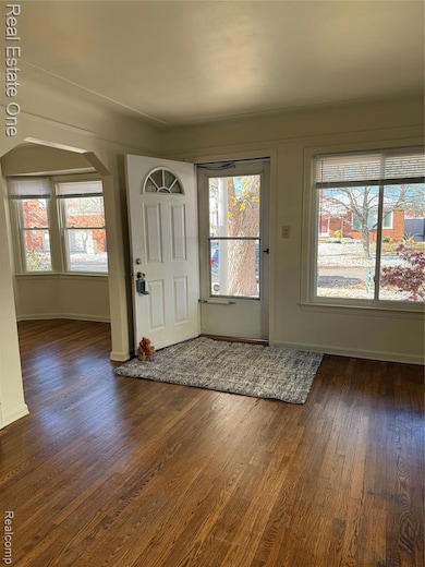 Entryway featuring arched walkways and dark wood-style flooring connected to dining room