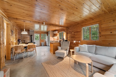 Living room featuring concrete flooring, a wall mounted air conditioner, and wood walls