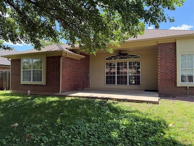 Back of property with a ceiling fan, brick siding, and a patio area
