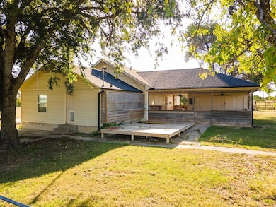 Back of house with roof with shingles, a ceiling fan, a yard, and a patio area