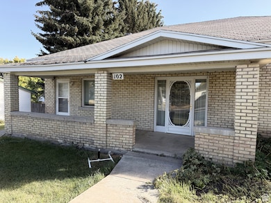 Entrance to property with brick siding, covered porch, a yard, and roof with shingles