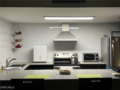 Kitchen featuring wall chimney exhaust hood, appli
