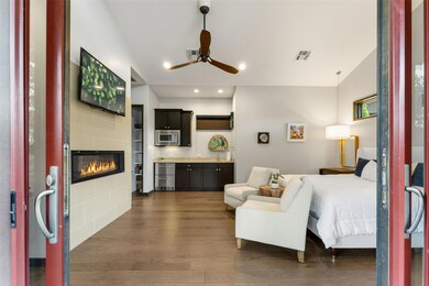 Bedroom featuring beverage cooler, a tile fireplace, dark wood finished floors, and recessed lighting