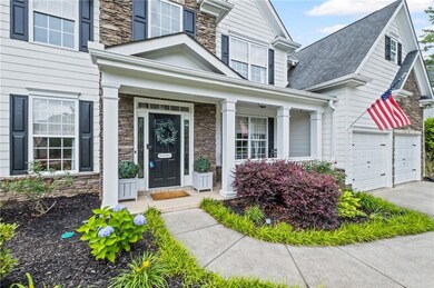 Doorway to property with stone siding, a garage, concrete driveway, and covered porch
