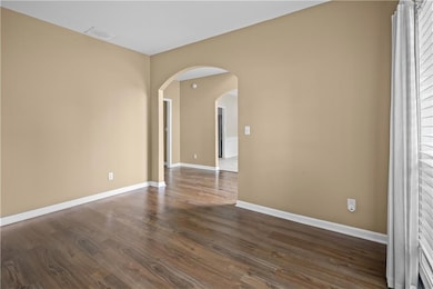 Unfurnished room with arched walkways and dark wood-style flooring