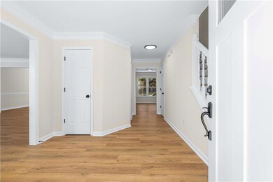 Corridor with ornamental molding and light wood finished floors