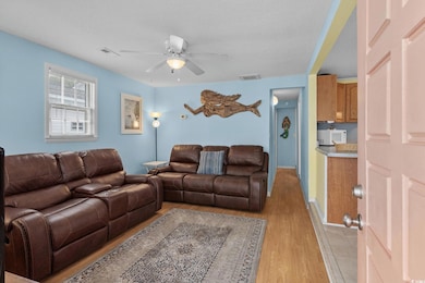 Living area featuring light wood finished floors, a textured ceiling, and a ceiling fan