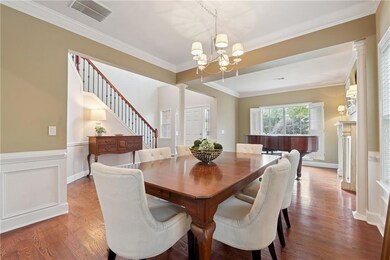 Dining space with crown molding, an inviting chandelier, columns, and wood finished floors