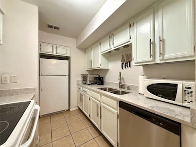 Kitchen with white appliances, light tile pattern