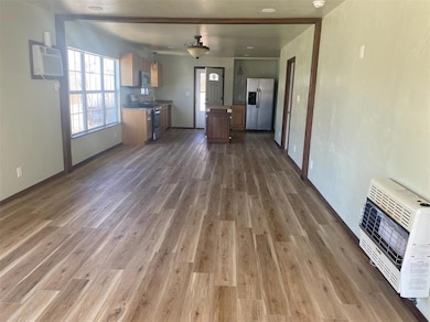 Unfurnished living room featuring heating unit, dark wood-type flooring, and a wall mounted air conditioner