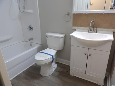 Full bath with toilet, wood finished floors, decor